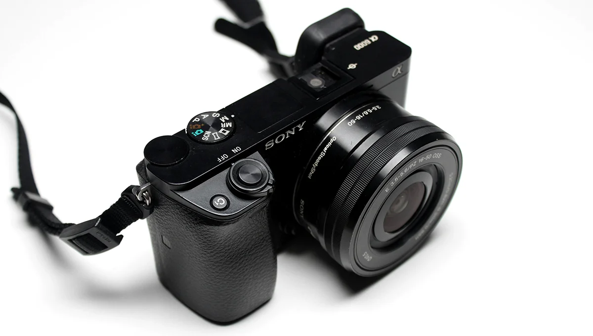 A compact camera with a strap attached, designed for easy carrying and photography on the go.