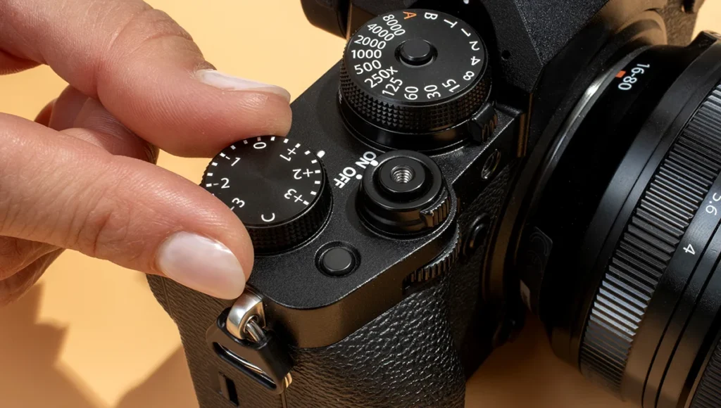 A person adjusts the focus setting on a camera, showcasing the best camera features with a visible dial.