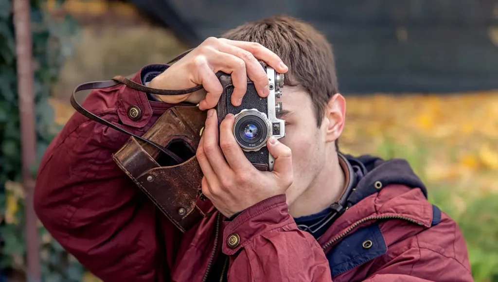 A young man taking a picture with vintage camera